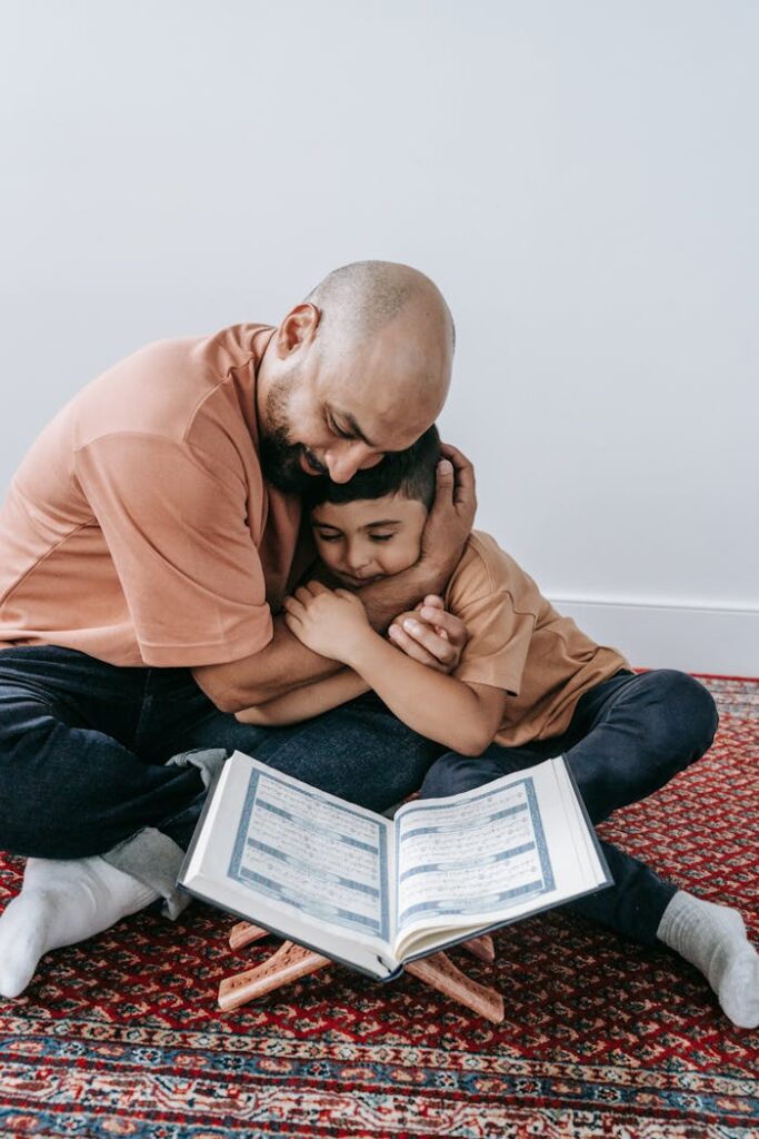 pexels-photo-9127745 Heartwarming moment of father and son hugging while reading a book together, showcasing love.